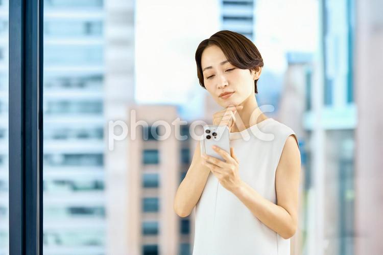 スマホを持つビジネスウーマン　オフィス ビジネスウーマン,スマホ,オフィスの写真素材