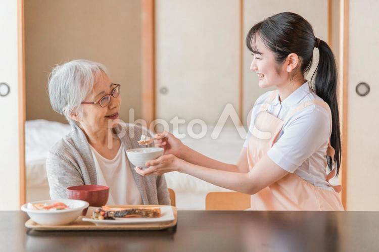 食事をする高齢者女性と女性スタッフ（食事介助） 食事介助,介助,食事の写真素材