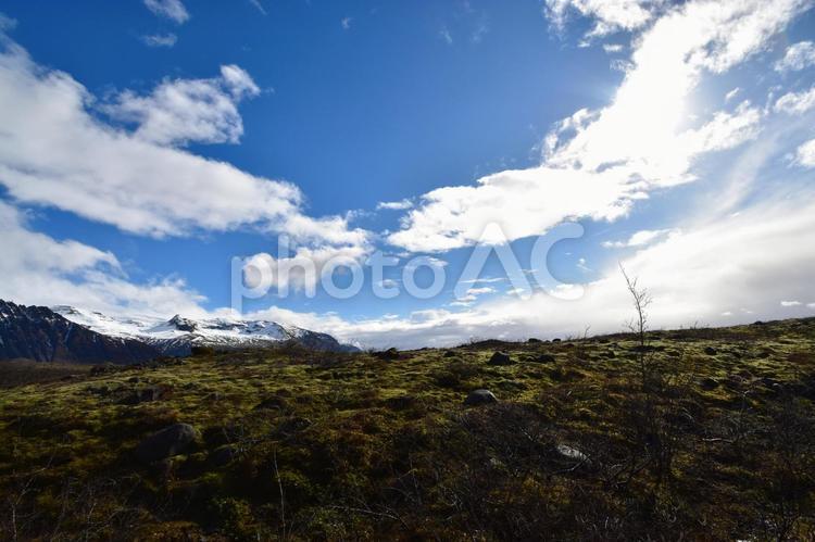 太陽と雪山と苔の丘が広がる絶景 アイスランド,風景,景色の写真素材