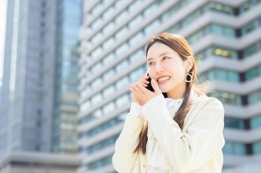 ビル街で電話をする女性 ビル街で電話をする女性 スマホ,元気,キャリアウーマンの写真素材
