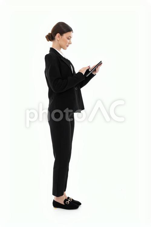 立ち止まりタブレットを操作する横向き女性 女性,タブレット,スマートフォンの写真素材