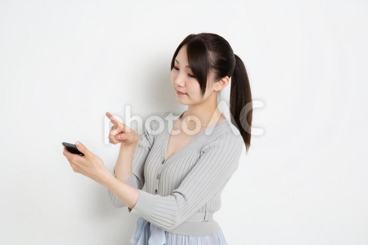 スマートフォンで検索をしているポニーテールの女性 女,女性,日本人の写真素材