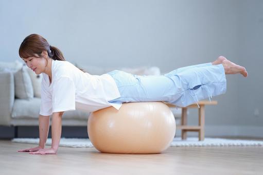 うつ伏せでバランスボールにのる女性 女性,バランスボール,うつ伏せの写真素材