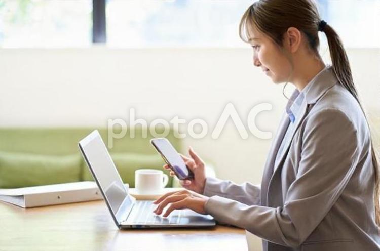 カフェでパソコンとスマホを操作する女性 パソコン,女性,アジア人の写真素材