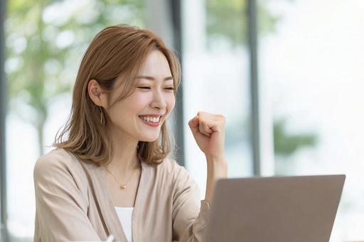 PC前で笑顔のガッツポーズ女性の写真