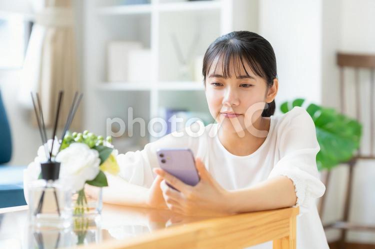 リビングでスマホを見る大学生の女性 女性,スマホ,大学生の写真素材