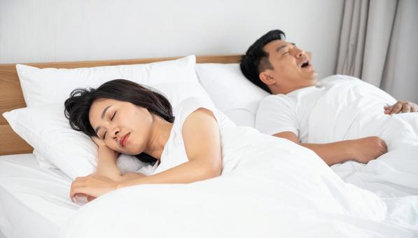 ベッドで夫のいびきで睡眠不足の妻 ベッドで夫のいびきで睡眠不足の妻の写真