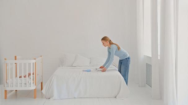 ベッドの上にベビー服を置く横向き女性 ベッドの上にベビー服を置く横向き女性 女性,横向き,横顔の写真素材