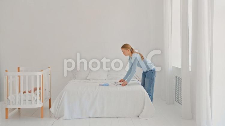 ベッドの上にベビー服を置く横向き女性 女性,横向き,横顔の写真素材
