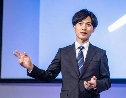 ステージ上で堂々とプレゼンする男性 ステージ上で堂々とプレゼンする男性の写真