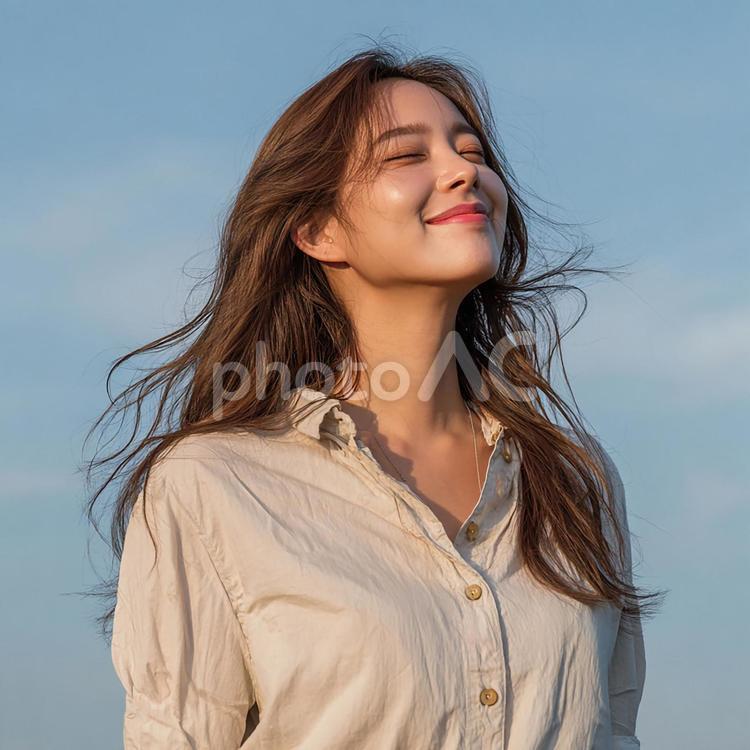穏やかな表情で空を見上げる若い女性 女性,アジア人,自然光の写真素材