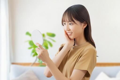鏡で肌をチェックする若い女性 女性,美容,スキンケアの写真素材