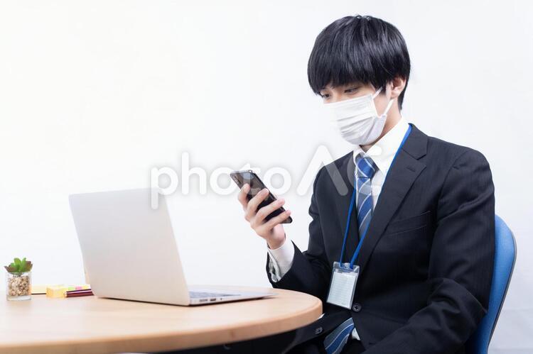 マスクをしてスマートフォンを見る日本人男性会社員 白バック,白背景,スーツの写真素材