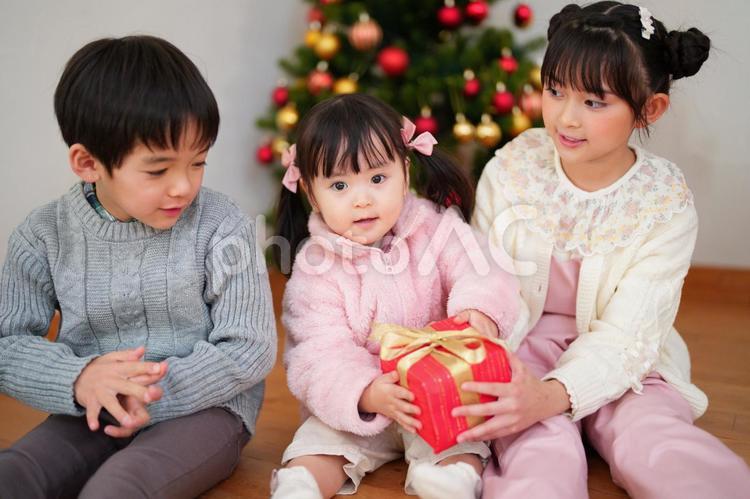 赤い箱を持つ女の子を見る子供たち 男女,クリスマス,プレゼントの写真素材
