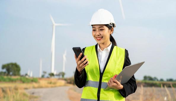 ファイルを見て携帯で指示を出す作業着女性 ファイルを見て携帯で指示を出す作業着女性の写真