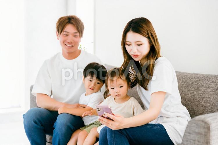 家のリビングでスマホを見る日本人家族 スマホ,家族,アプリの写真素材