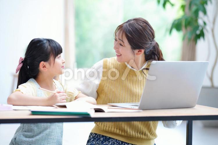 宿題中に横の母を見る女の子 母,ノートパソコン,娘の写真素材