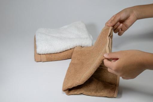 白と茶色のタオルを畳む手元 タオル,畳む,手の写真素材