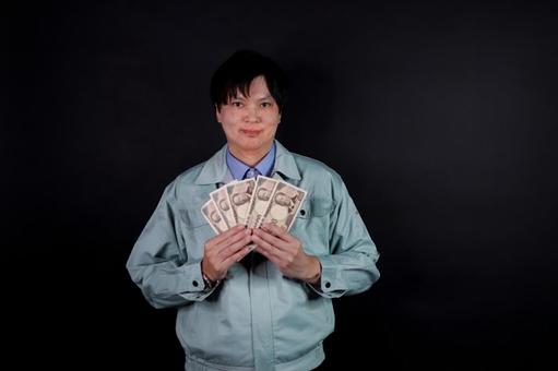 現金を持つ作業服の男性 現金を持つ作業服の男性の写真
