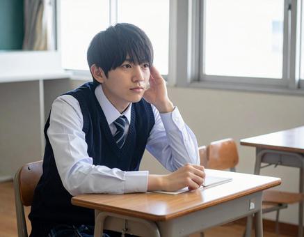 授業中に頭を抱えて悩む男子学生 授業中に頭を抱えて悩む男子学生の写真