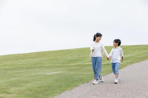 丘の上を笑顔で歩く子ども 丘の上を笑顔で歩く子どもの写真