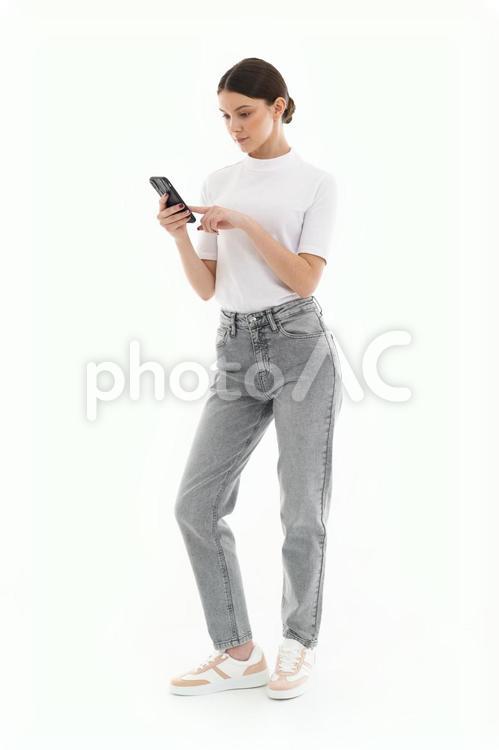 スマホを操作する白いTシャツの女性 女性,微笑む,スマートフォンの写真素材