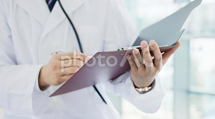  書類に記入する男性医師の手元 医師,医者,書類の写真素材