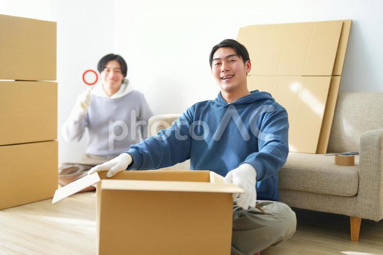 引っ越しの荷造り中の男性とマルの札を持つ男性 引っ越し,一人暮らし,男性の写真素材