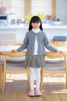 明るい部屋でテーブルに手を置いて立つ女の子 女の子,笑顔,嬉しいの写真素材