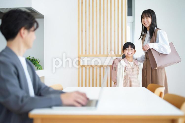 座ってパソコンで仕事する男性とランドセルの女の子と女性 女の子,女性,男性の写真素材