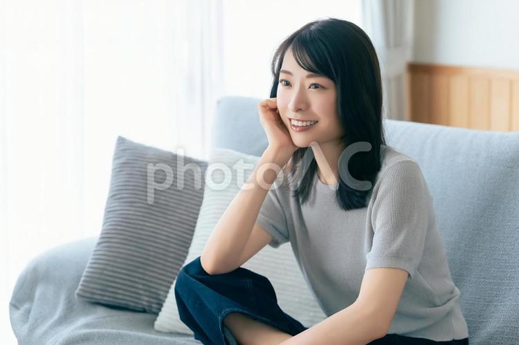 リビングのソファに座る笑顔の女性 女性,ソファ,微笑むの写真素材