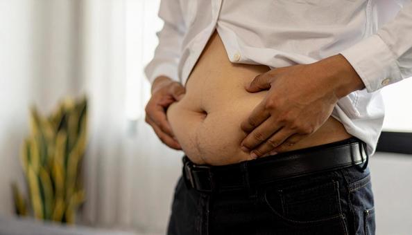 メタボリックなお腹に手を触れる男性 メタボリックなお腹に手を触れる男性の写真