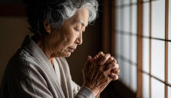 うつむいて手を組んで座る日本人シニア女性 うつむいて手を組んで座る日本人シニア女性の写真