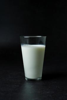 黒背景のコップに入った牛乳の写真