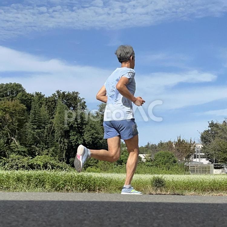 畑の横をジョギングするランナー 男性,男,走るの写真素材