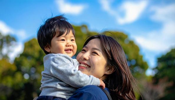 青空の下、子供を抱っこする母親 青空の下、子供を抱っこする母親の写真