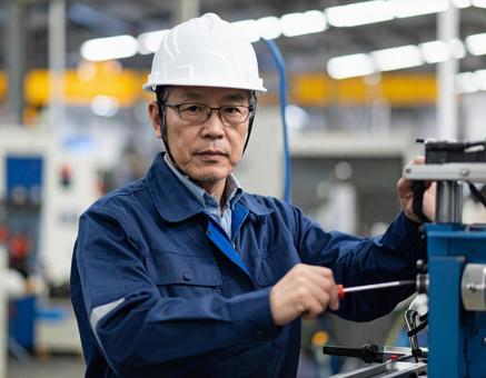 工場で機械を組み立てるベテラン作業員 工場で機械を組み立てるベテラン作業員の写真