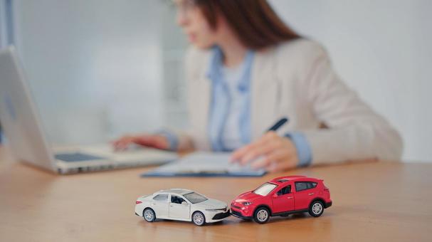車の模型を前にノートPCを使う女性 保険業,事務職,接客業の写真素材