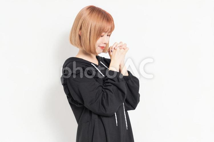 お願いのジェスチャーをするカジュアルな服装の若い女性 お願い,祈る,祈りの写真素材