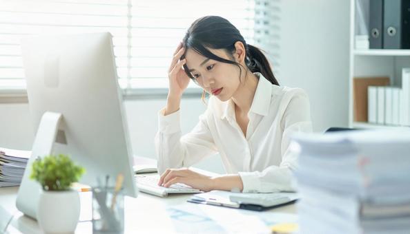 デスクで頭を抱えているビジネスマンの写真