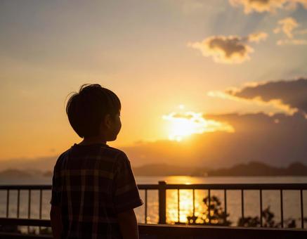 夕焼けの空を見つめる日本人の少年 夕焼けの空を見つめる日本人の少年の写真