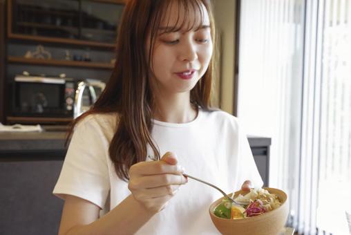 彩り豊かなサラダを食べる女性 彩り豊かなサラダを食べる女性の写真