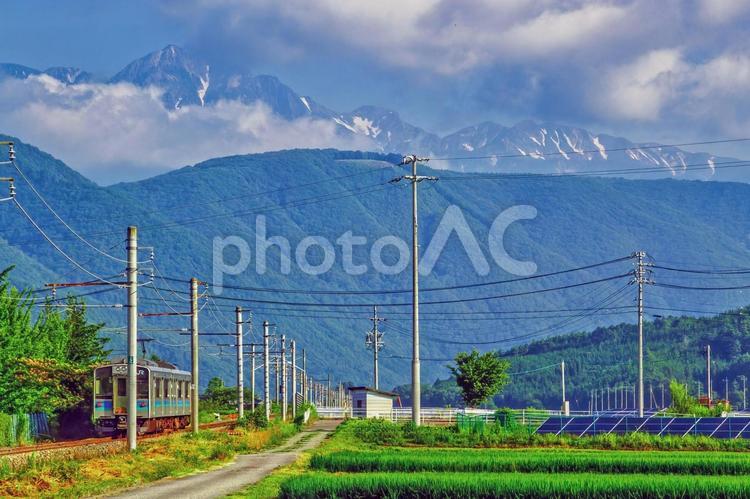 信州の夏景色、山々を背景に走るローカル線 長野,大町,北アルプスの写真素材