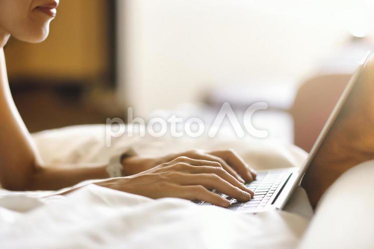 室内のベッドでラップトップを使用する女性 パソコン,ラップトップ,ノートパソコンの写真素材