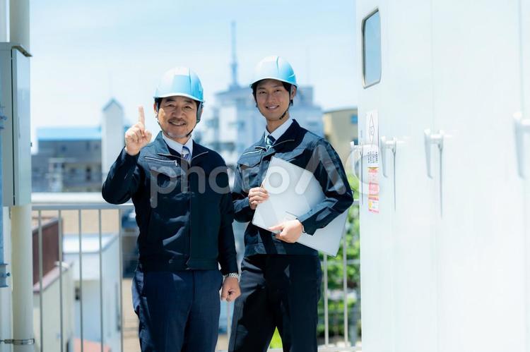 現場で打ち合わせする作業服のビジネスマン 作業服,打ち合わせ,ヘルメットの写真素材