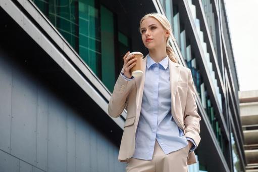 オフィスビルの外でコーヒーを持って立つビジネスウーマン ビジネスウーマン,ビジネス,女性の写真素材
