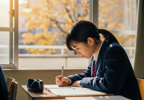 秋の教室で勉強に集中する女子学生の写真