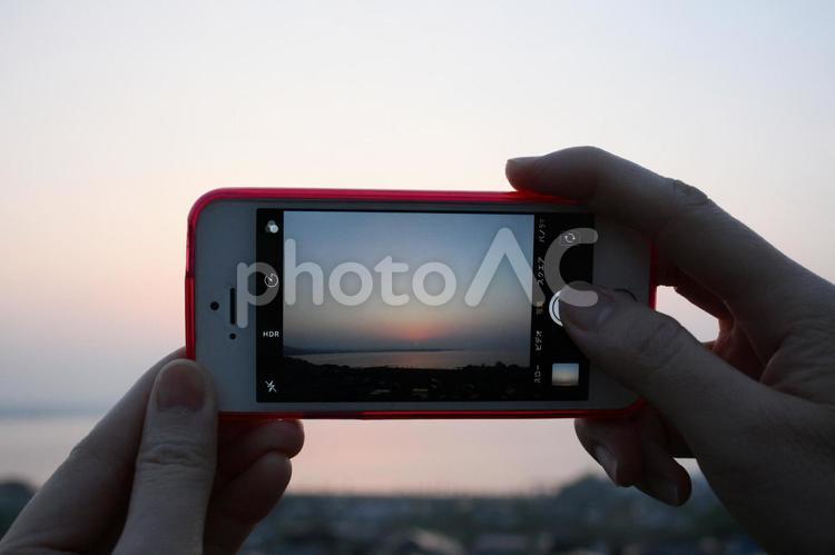 スマートフォンで日の出写真を撮る女性の手 風景,自然,太陽の写真素材