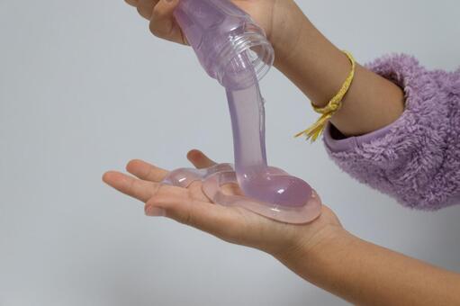 容器から流れ出る紫色のスライム スライム,手,流れるの写真素材