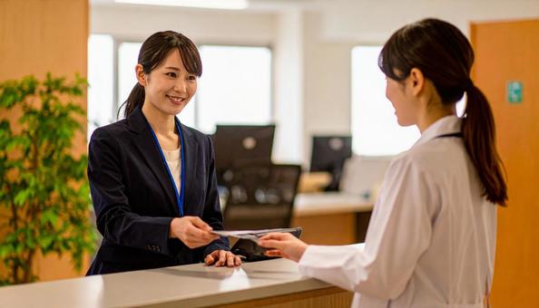 病院の会計窓口で会計をする女性患者 病院の会計窓口で会計をする女性患者の写真